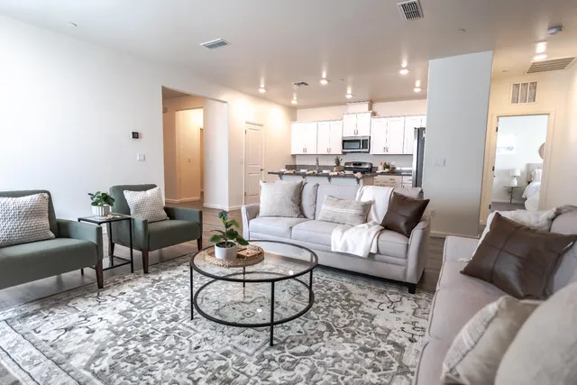 a living room with furniture wooden floor and kitchen view