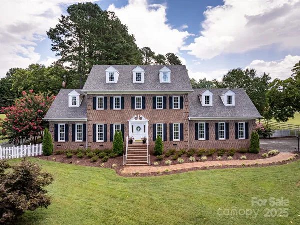 a front view of a house with a garden and trees