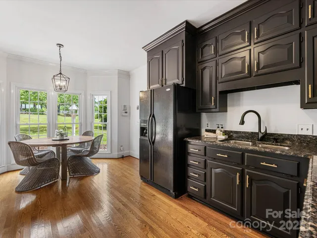 a kitchen with stainless steel appliances granite countertop a stove a refrigerator a sink dishwasher a dining table and chairs with wooden floor