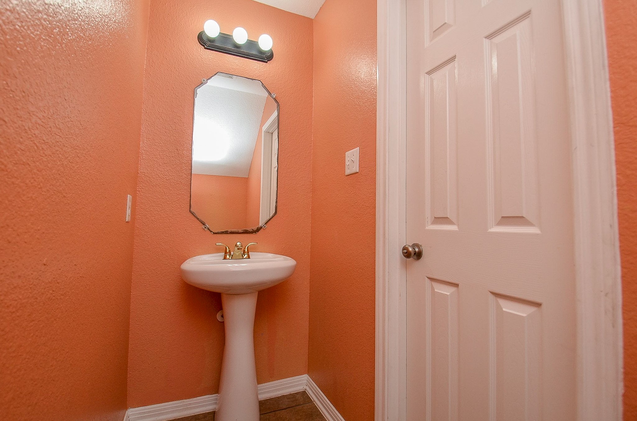 5411 Rio Drive Baytown, TX 77521 - Photo 14 of 30 The main level powder room features a pedestal sink and decorative mirror.
