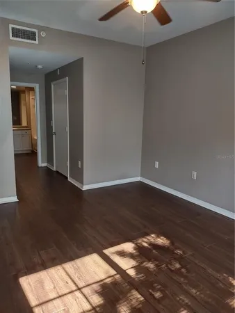 an empty room with wooden floor chandelier fan and windows