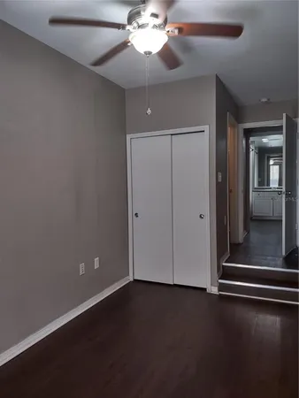 an empty room with wooden floor fan and windows