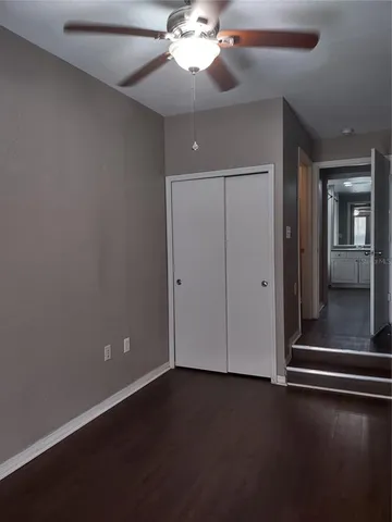 an empty room with wooden floor fan and windows