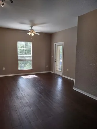a view of an empty room with wooden floor and a window