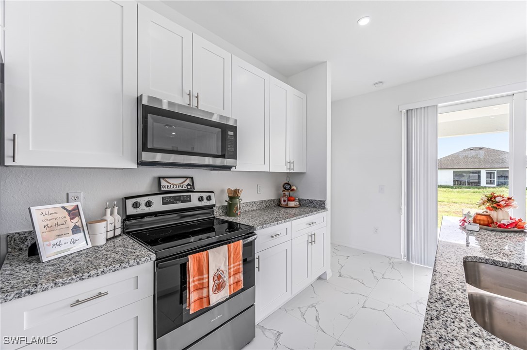 2102 Robert Avenue Alva, FL 33920 - Photo 11 of 24 a kitchen with stainless steel appliances granite countertop a stove a sink and a microwave