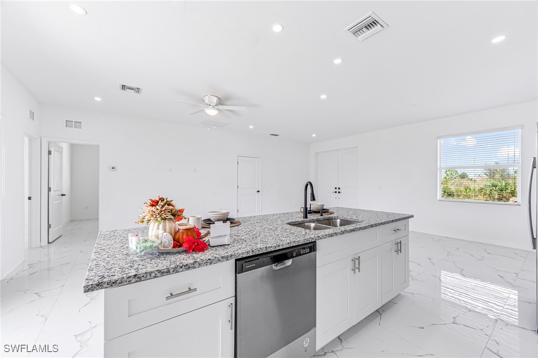 2102 Robert Avenue Alva, FL 33920 - Photo 12 of 24 a kitchen with stainless steel appliances granite countertop a sink dishwasher and white cabinets with wooden floor