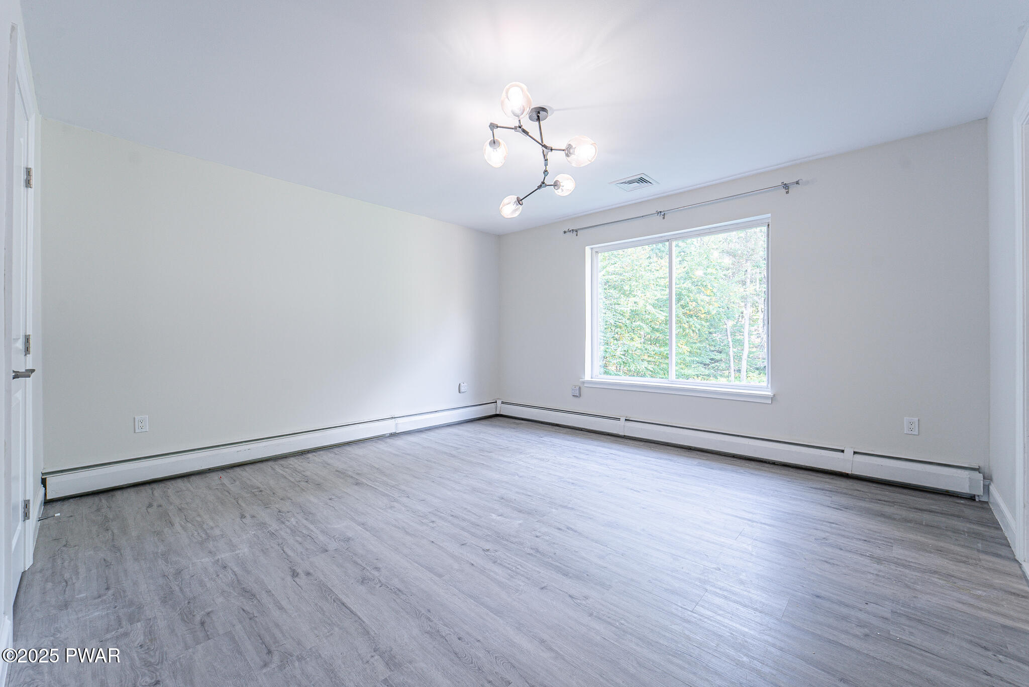 153 Hatton Road Hawley, PA 18428 - Photo 13 of 38 an empty room with wooden floor chandelier fan and windows