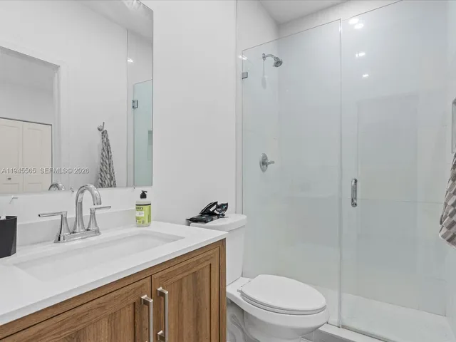 a bathroom with a granite countertop sink a toilet and shower