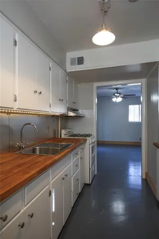a kitchen with stainless steel appliances granite countertop a sink a stove and dishwasher with wooden floor