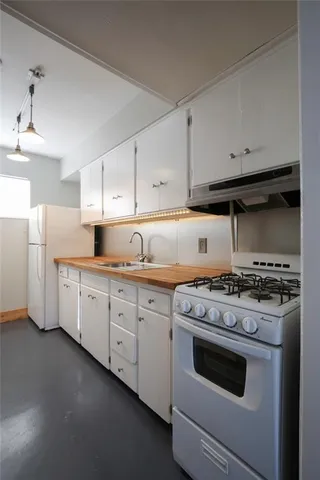 a kitchen with granite countertop white cabinets and white stove