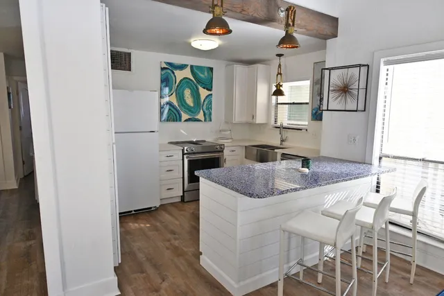 a living room with furniture kitchen view and a chandelier