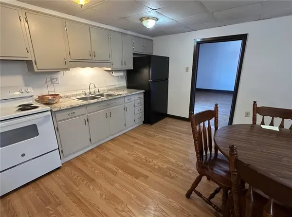 a kitchen with stainless steel appliances granite countertop a stove a refrigerator a sink a dining table and chairs with wooden floor
