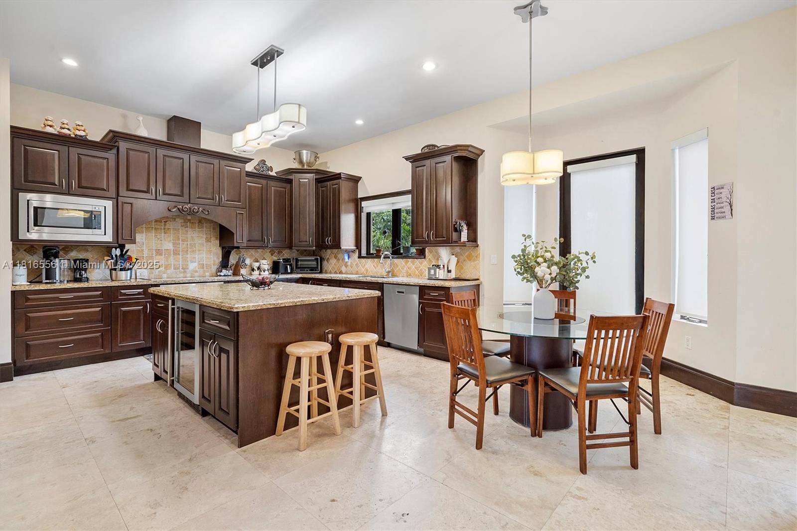 18825 North Bay Road Sunny Isles Beach, FL 33160 - Photo 26 of 62 a kitchen with stainless steel appliances granite countertop a stove a sink a refrigerator and a dining table with wooden cabinets