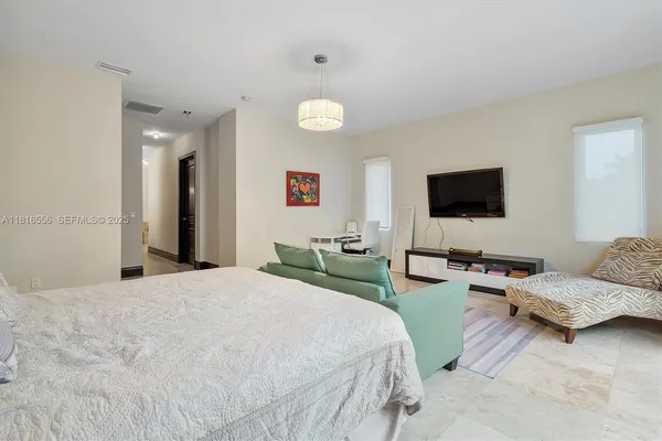 a bedroom with a bed and a flat tv screen on dresser