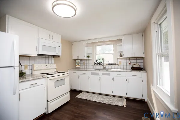 a kitchen with cabinets appliances wooden floor and a window