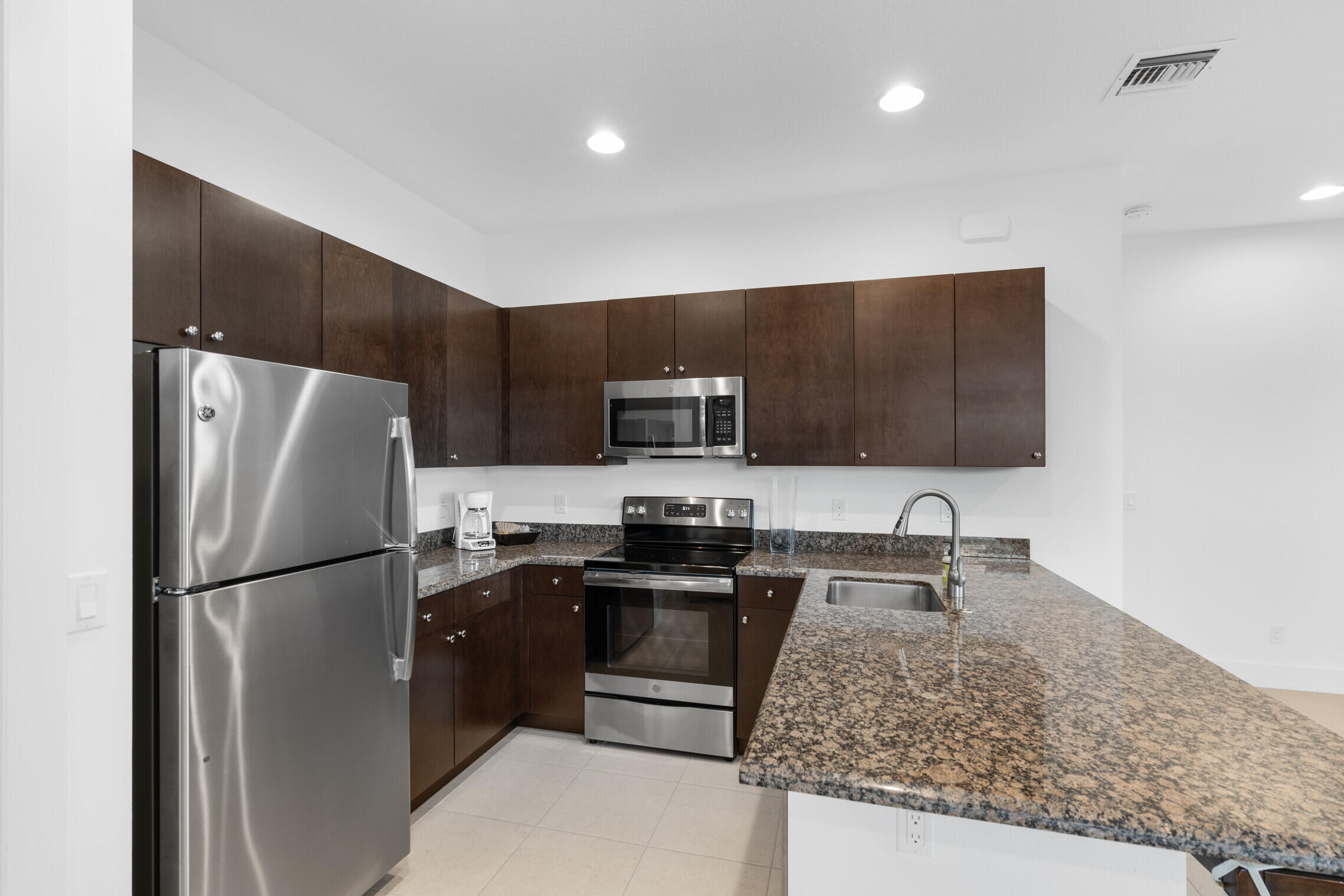 4084 Faraday Way Palm Beach Gardens, FL 33418 - Photo 34 of 43 a kitchen with stainless steel appliances granite countertop a refrigerator a stove a sink and a microwave