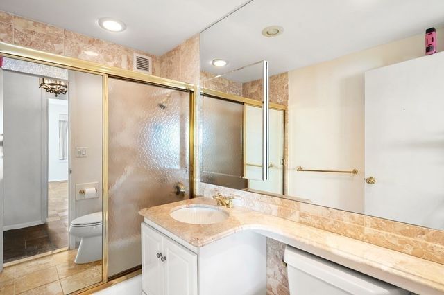 a bathroom with a granite countertop sink mirror and shower