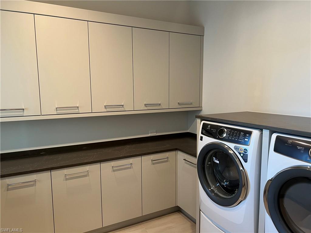 6708 Newport Road Naples, FL 34109 - Photo 17 of 48 Laundry area with washer and dryer, cabinet space, and light wood-style floors