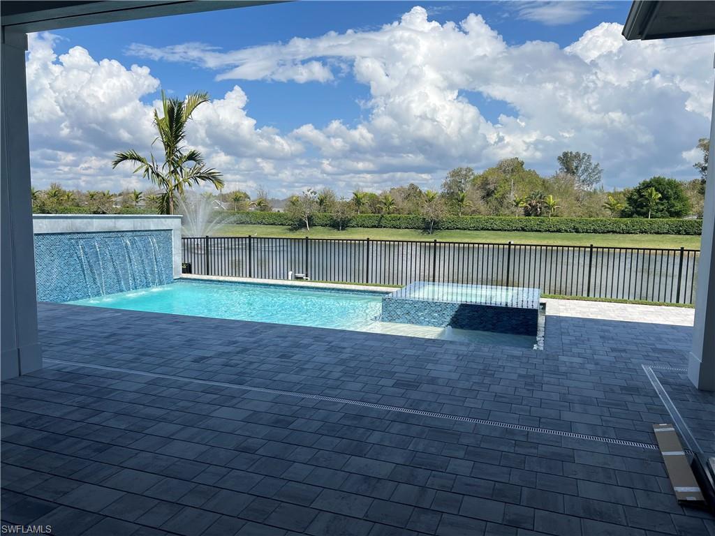6708 Newport Road Naples, FL 34109 - Photo 8 of 48 Relaxing pool / spa with a patio area, view of wooded area, a water view, and a fenced backyard