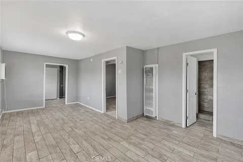 a view of an empty room with wooden floor and closet