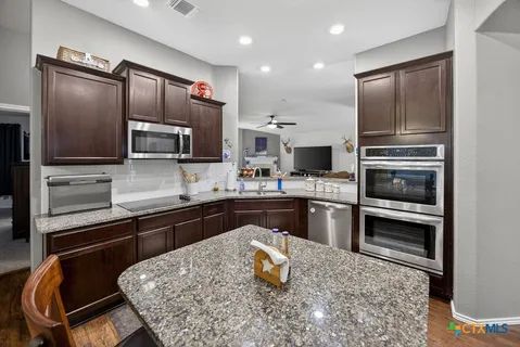 a kitchen with kitchen island granite countertop stainless steel appliances and a counter space