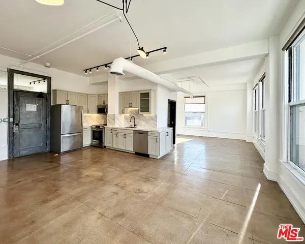 a view of a kitchen with refrigerator and white cabinets