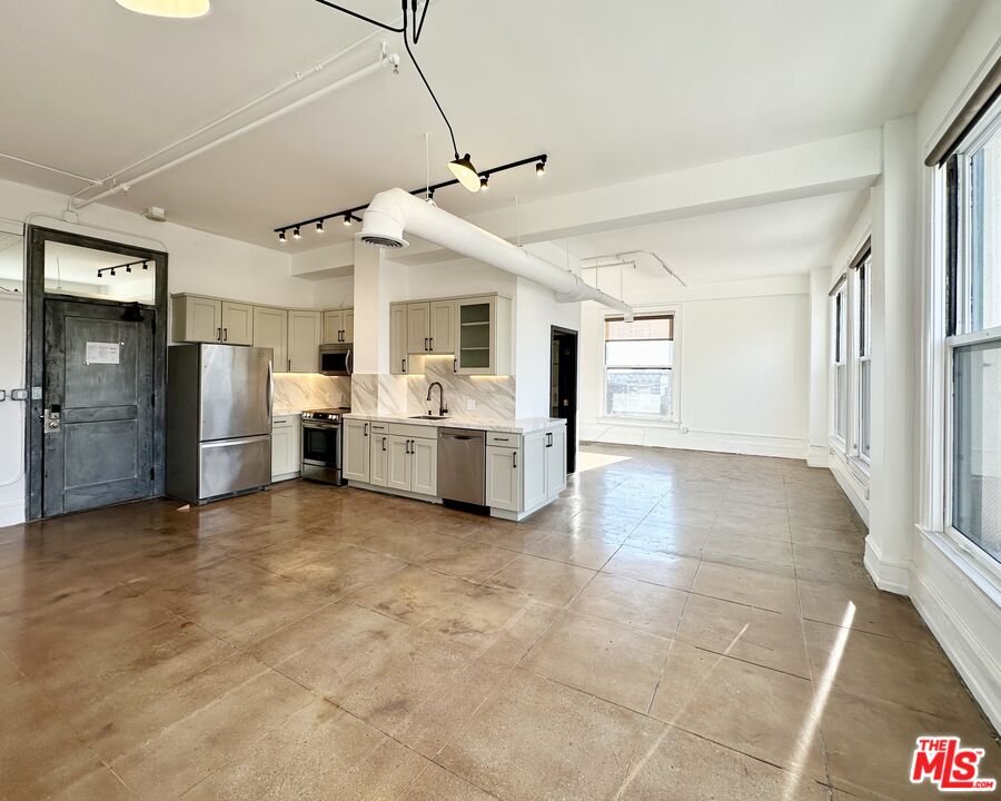 a view of a kitchen with refrigerator and white cabinets