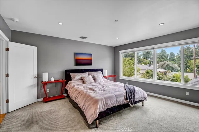 a bed sitting in a spacious bedroom next to a window