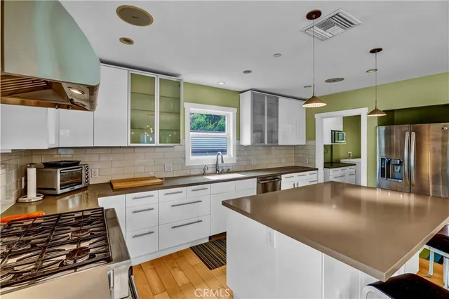 a kitchen with stainless steel appliances granite countertop a sink a stove and a refrigerator