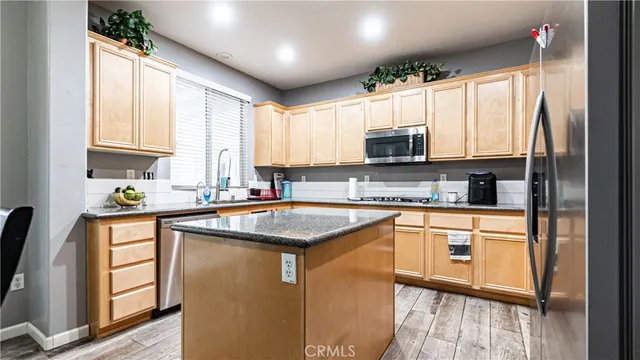 a kitchen with stainless steel appliances granite countertop a refrigerator a stove a sink and a microwave