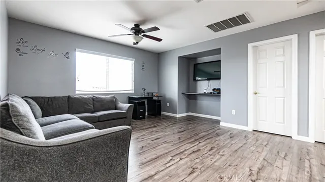 a view of empty room with wooden floor and fan