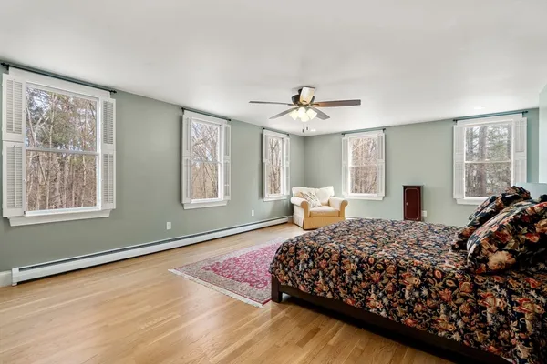 a bedroom with a large bed and wooden floor