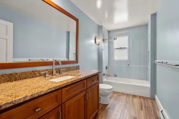 a bathroom with a granite countertop sink a toilet and bathtub