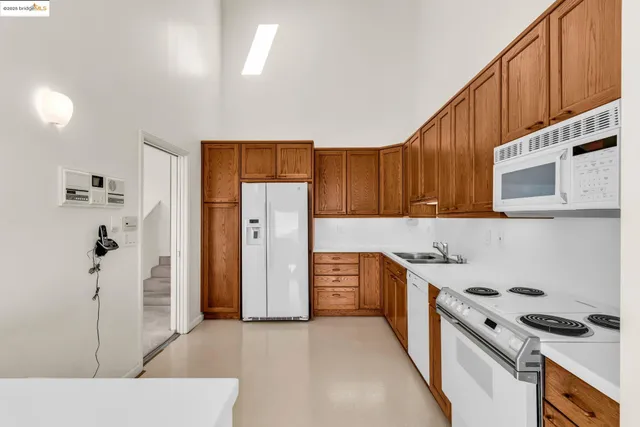 a kitchen with stainless steel appliances granite countertop a refrigerator a stove and a sink with wooden cabinets