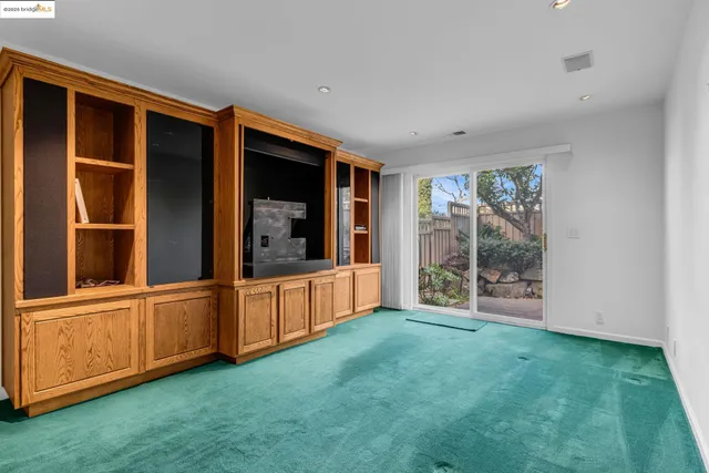 a view of an empty room with window and hardwood