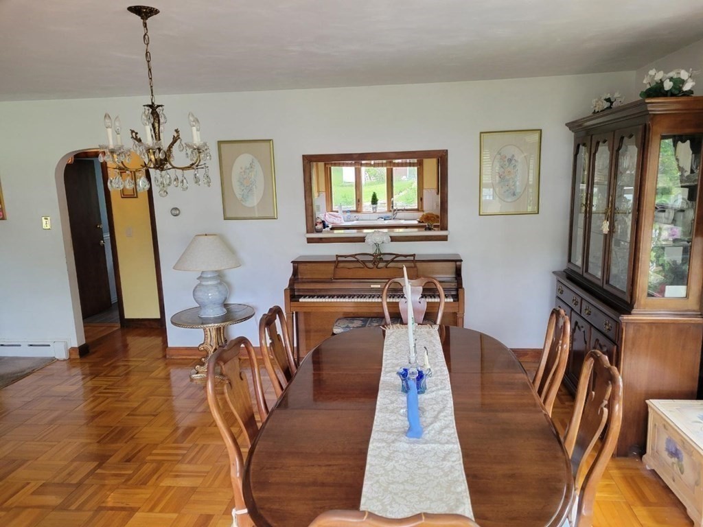 235 Belchertown Road Ware, MA 01082 - Photo 18 of 27 a dining room with wooden floor a chandelier a wooden table and chairs