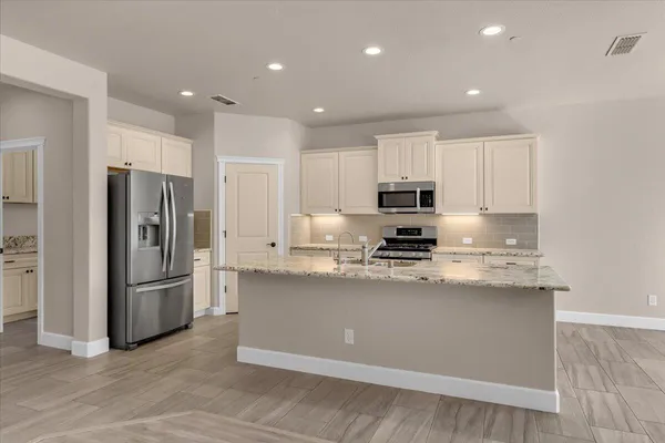 a large kitchen with stainless steel appliances granite countertop a lot of counter space and wooden cabinets