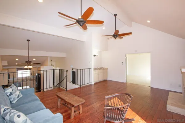 a view of a livingroom with a furniture wooden floor a ceiling fan and windows
