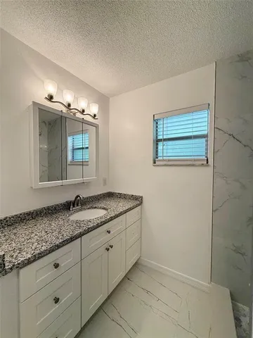 a bathroom with a granite countertop sink and a mirror