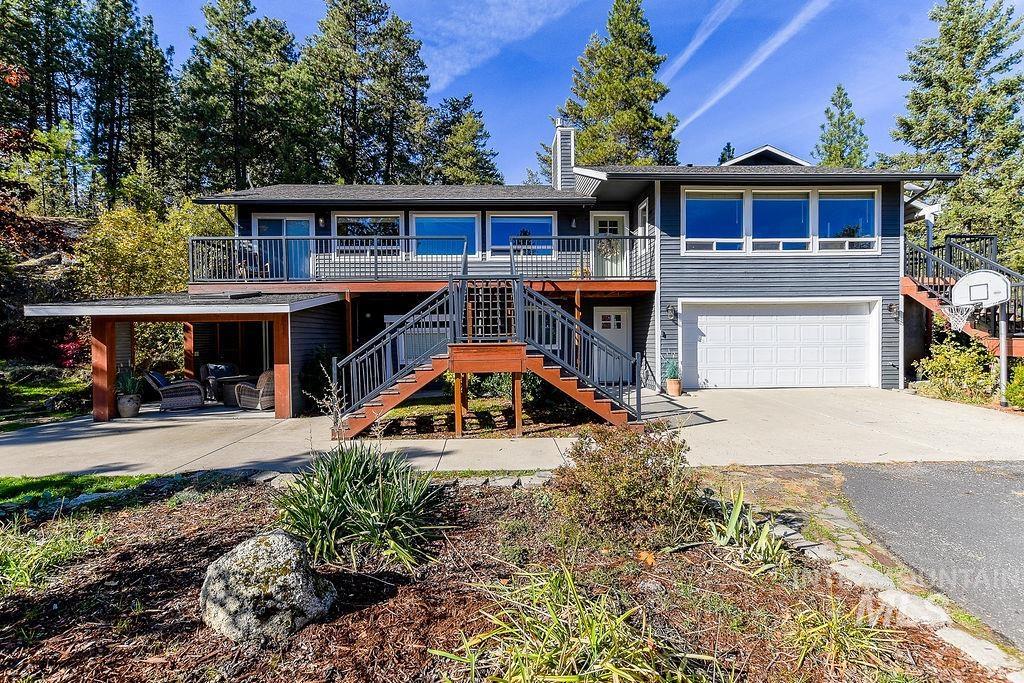 View of front of home featuring stairway, concrete driveway, a chimney, and a deck