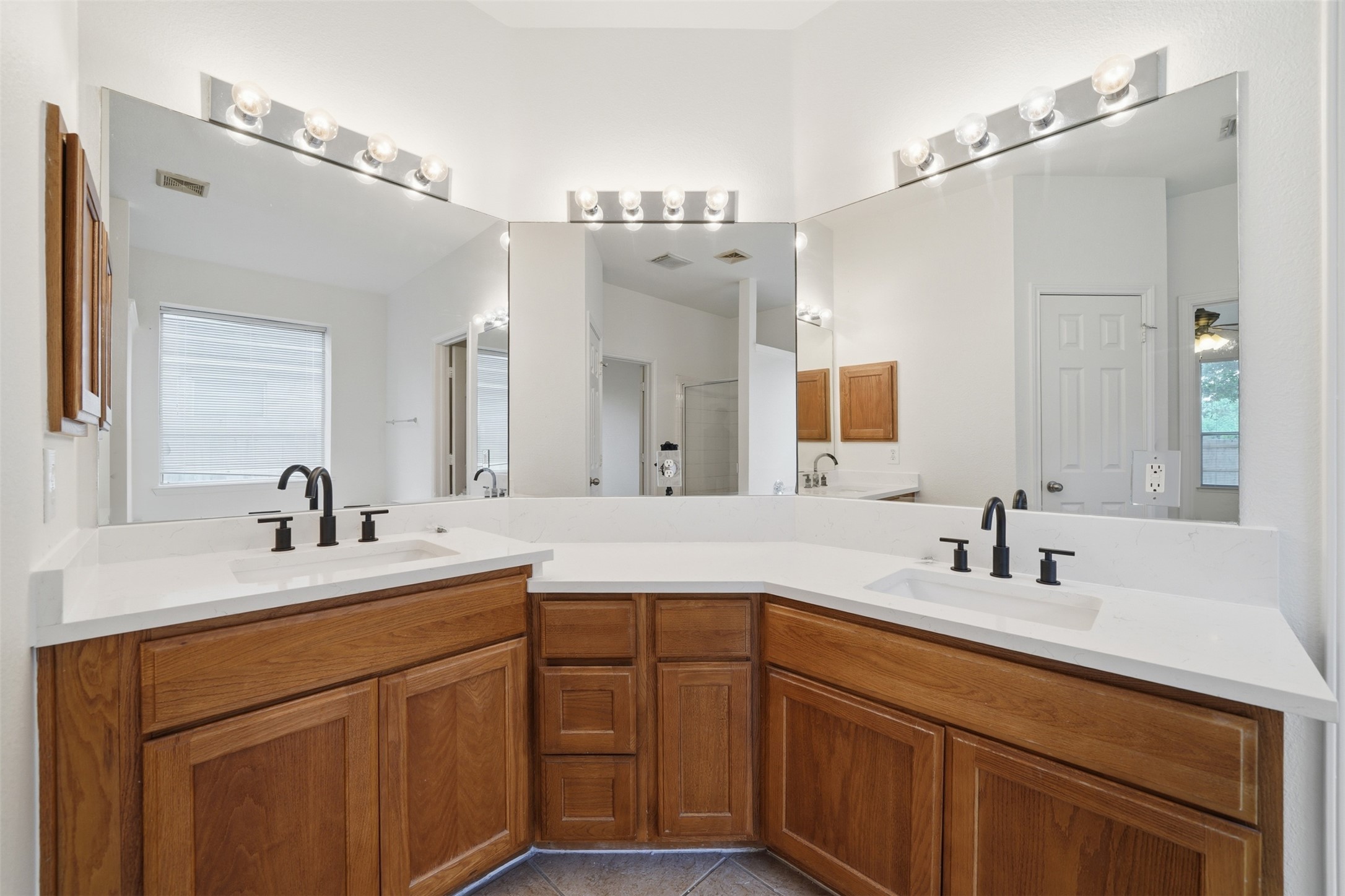 118 Invierno Street Kyle, TX 78640 - Photo 27 of 37 Double vanity with pristine countertops and warm wooden cabinetry awaits in this spacious primary bathroom.