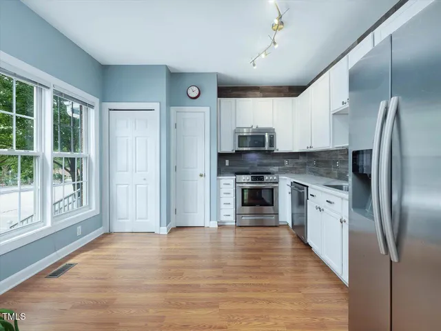 a view of kitchen with stainless steel appliances wooden floor and window