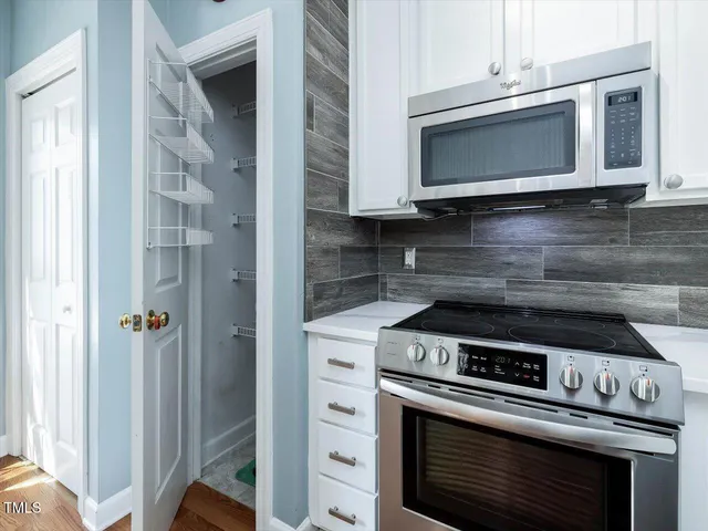 a view of a kitchen from a hallway with a stove and a microwave