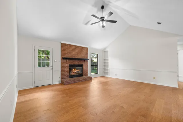 an empty room with windows and fireplace