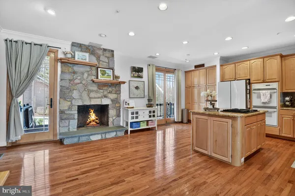 a kitchen with stainless steel appliances granite countertop a stove top oven a refrigerator a sink and a fireplace with wooden floor