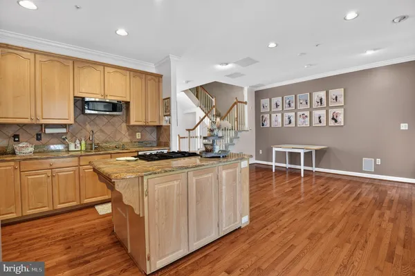 a kitchen with stainless steel appliances granite countertop a stove a sink and white cabinets with wooden floor