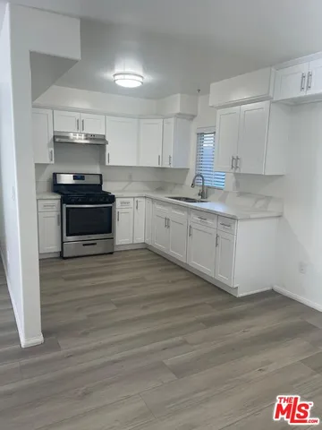 a kitchen with stainless steel appliances wooden floor and a sink