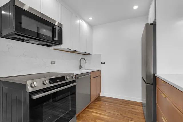 a kitchen with stainless steel appliances a stove top oven a sink dishwasher a refrigerator and a microwave