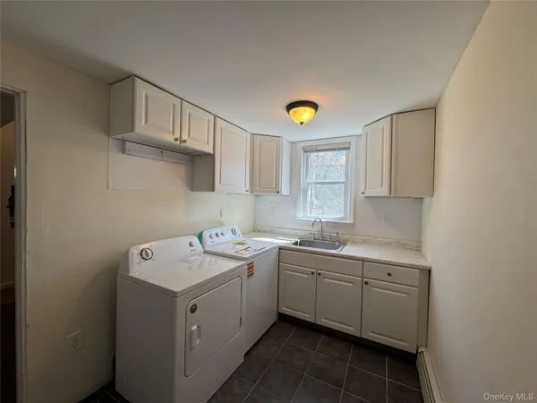 a utility room with a sink a window and cabinets