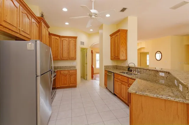 a large kitchen with stainless steel appliances granite countertop a refrigerator and a sink